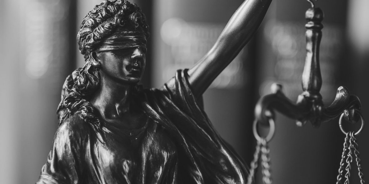 Blindfolded Justice holding up the scales with close up focus to her face over a coppery colored background