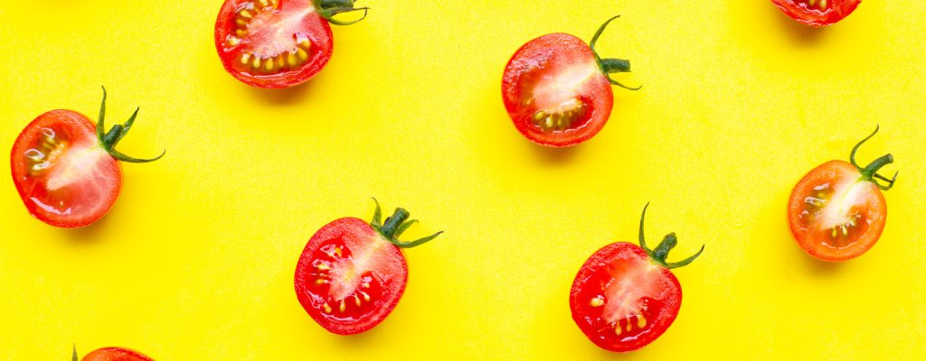 Fresh cherry tomatoes, half cut isolated on yellow background. Top view